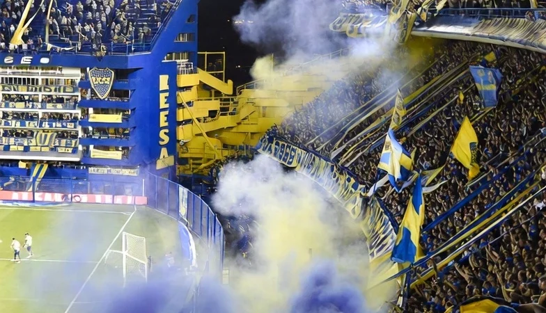 Passionate Boca Juniors fans inside La Bombonera stadium during an intense night football match in Buenos Aires.